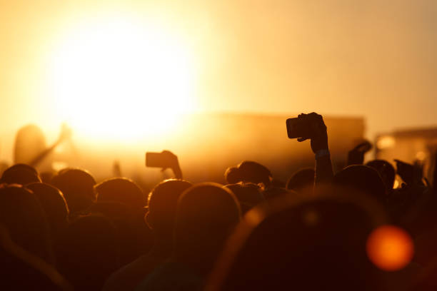 istock Silhouette of smartphone in a hand over crowd. 910707254