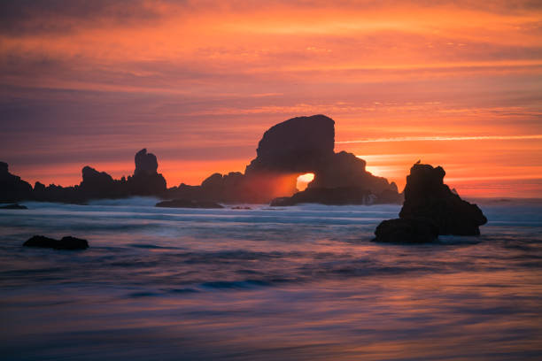 This is a slow shutter shot of the sunset behind arch at Oregon coast of USA. Time lapse video also available at https://www.istockphoto.com/video/sunset-behind-arch-at-oregon-coast-usa-gm907438078-249999954