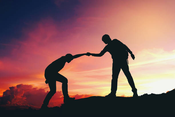 istock Teamwork couple helping hiking each other silhouette on mountains 910730596