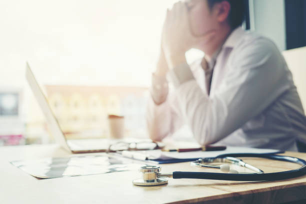 stethoscope and doctor sitting with laptop stress headache about work in hospital - medicine cabinet medicine healthcare and medicine cabinet imagens e fotografias de stock