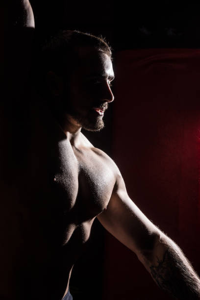 silhouette der muskulösen mann auf dunkelroten hintergrund - sensuality men shirtless studio shot stock-fotos und bilder