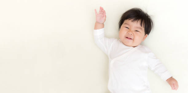 adorabile bambina asiatica sorride e mostra la mano sul letto.  (banner panoramico) - triteleia ixioides foto e immagini stock