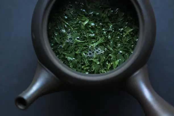 Japoanese sencha, green tea, brewing in a Tokoname teapot on black slate.