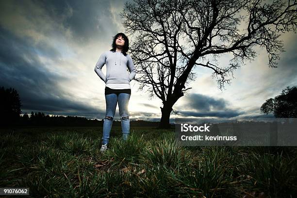 Girl Standing In Front Of Árbol Y La Puesta De Sol Foto de stock y más banco de imágenes de Adulto - Adulto, Adulto joven, Aire libre