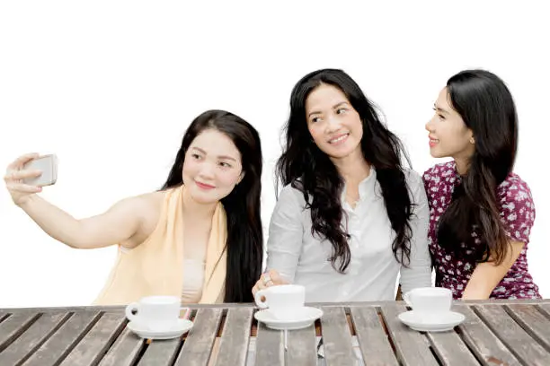 Picture of young three women enjoying coffee while taking a selfie picture together, isolated on white background