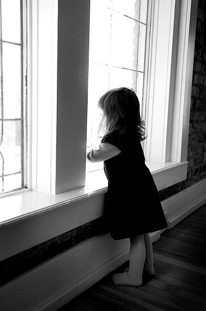 Little girl looking out window stock photo