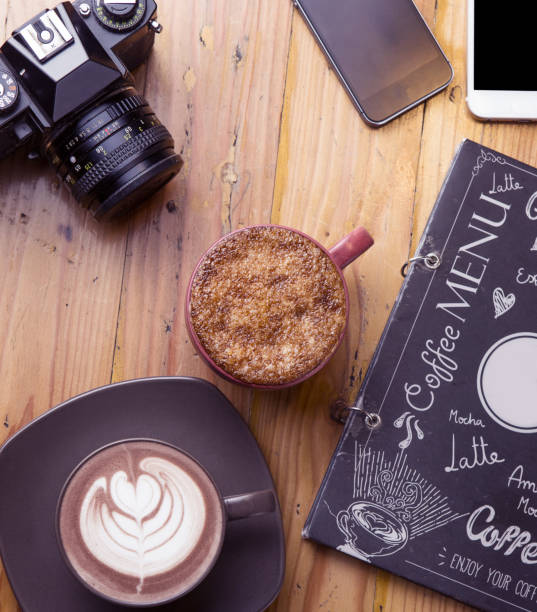 istock Cappuccino, creme brulee coffee latte, and camera on wooden background 910779600