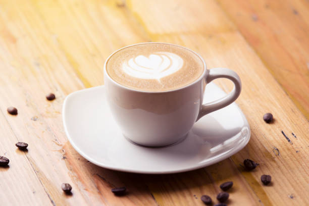 istock Cappuccino latte coffee with coffee beans on wooden table background 910779920