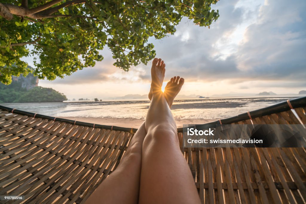 Personal perspective of woman relaxing on hammock, feet view Female's point of view from hammock on the beach at sunrise, barefoot. Beach Stock Photo