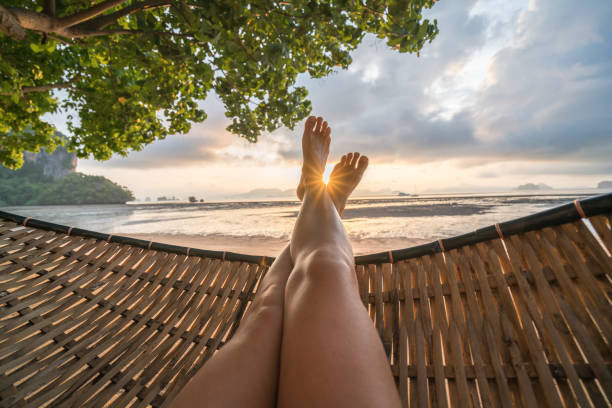 Personal perspective of woman relaxing on hammock, feet view Female's point of view from hammock on the beach at sunrise, barefoot. hammock stock pictures, royalty-free photos & images