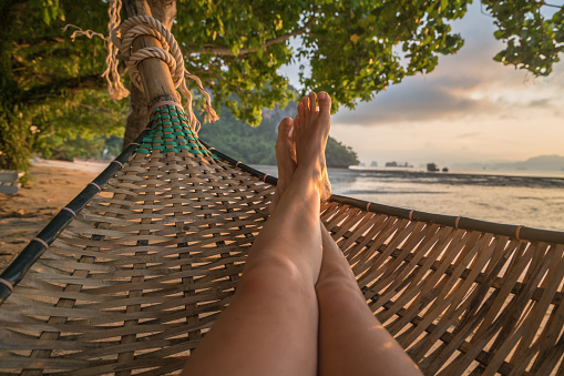 Female's point of view from hammock on the beach at sunrise, barefoot.