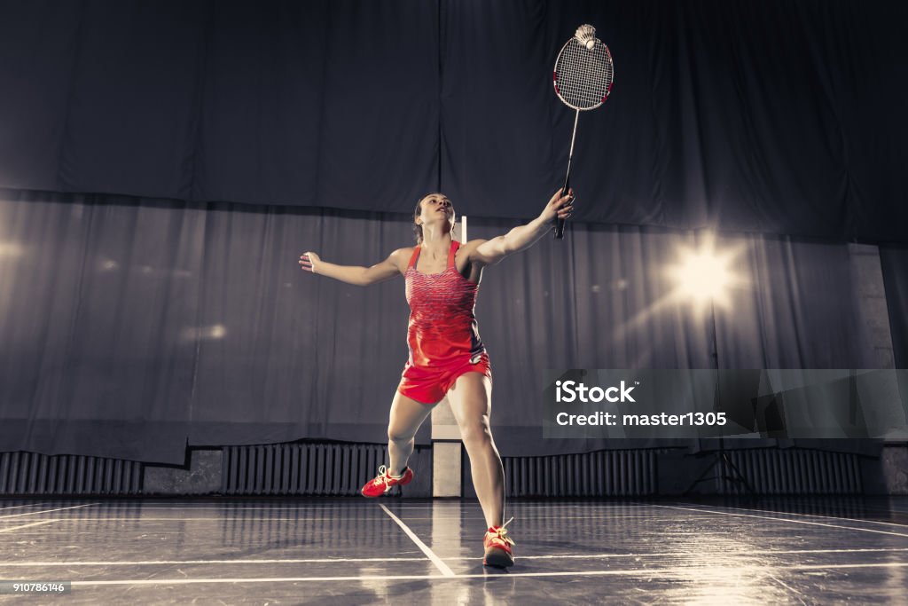 Young woman playing badminton at gym Young woman playing badminton over gym background Badminton - Sport Stock Photo