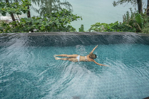 Young woman in private pool villa by the ocean, luxury vacations concept. Shot in Phuket, Thailand.