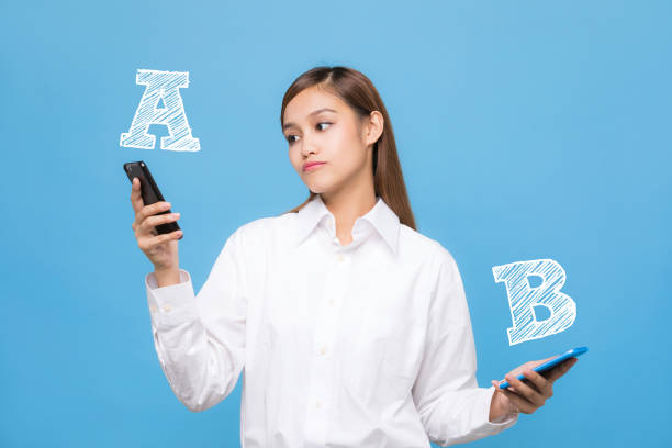 Young woman comparing smartphone A with smartphone B. Young woman comparing smartphone A with smartphone B. option key stock pictures, royalty-free photos & images