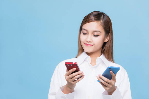 joven mujer sosteniendo dos teléfonos inteligentes. - skirt brown fotografías e imágenes de stock