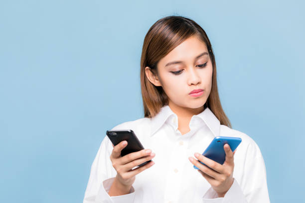 joven mujer sosteniendo dos teléfonos inteligentes. - skirt brown fotografías e imágenes de stock