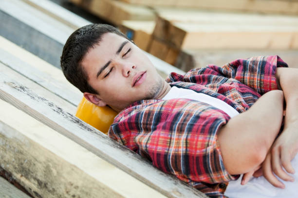 Lazy worker Construction worker sleeping outside. About 20 years, Caucasian male. lazy construction laborer stock pictures, royalty-free photos & images