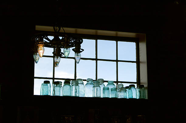 Antique canning jars along a vintage window sill- backlighted