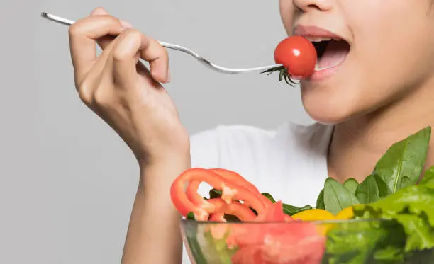 Photo of Young woman eating a salad.