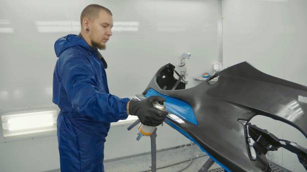 Serviceman preparing a car bodykit for painting in a workshop stock photo