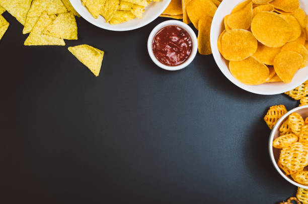 istock Potato chips and snacks on black slate table, top view 910798698