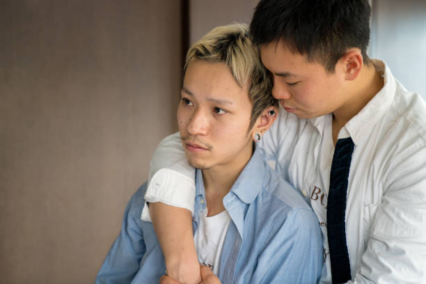 Young male couple embracing Young male couple embracing. Tokyo, Japan. January 2018 sad gay stock pictures, royalty-free photos & images