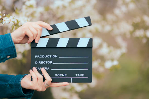istock Hands Holding Film Slate Cinema Clapper on Spring Blooming Background 910802620