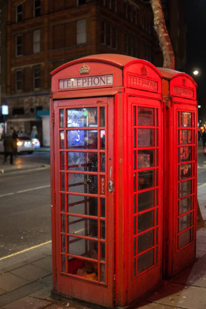 istock Red Telephone Box in the night in London with light reflections. 910813090