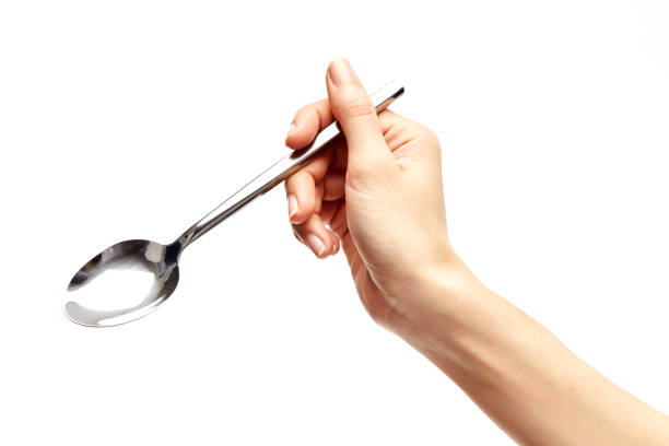 istock woman's right hand holds a spoon on a white background. 910820784