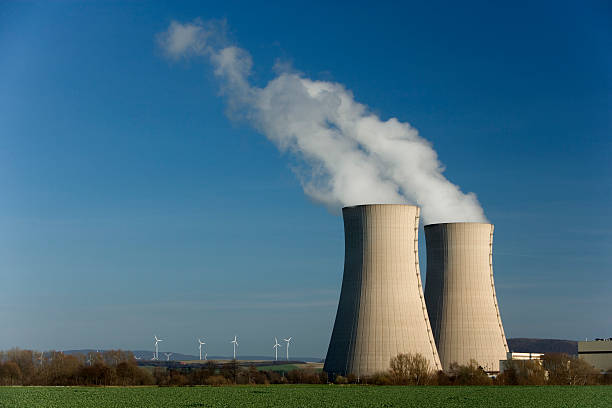 Long exposure of a nuclear power station with hill landscape and blue sky.