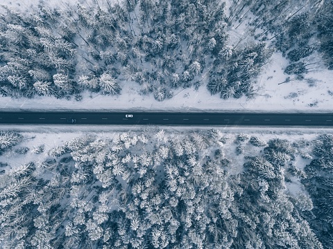 Country road going through the beautiful snow covered landscapes. Aerial view.