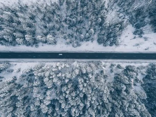 Photo of Country road going through the beautiful snow covered landscapes. Aerial view.