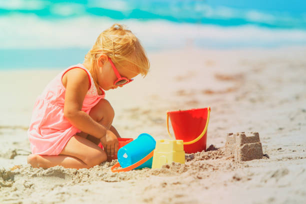 istock cute little girl play with sand on beach 910843814
