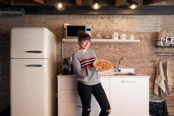 istock Beautiful girl eating pizza in a modern kitchen 910844020
