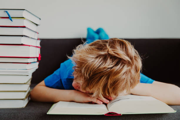 istock little boy tired stressed of reading, doing homework 910844612