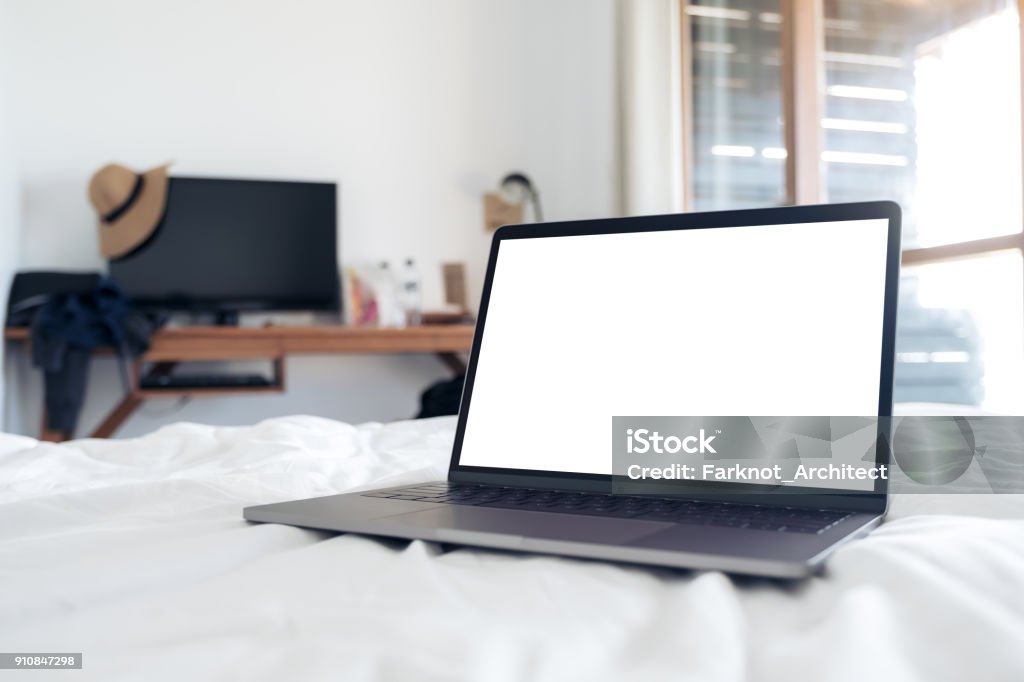 Mockup image of laptop with blank white desktop screen on the bed in bedroom Bed - Furniture Stock Photo
