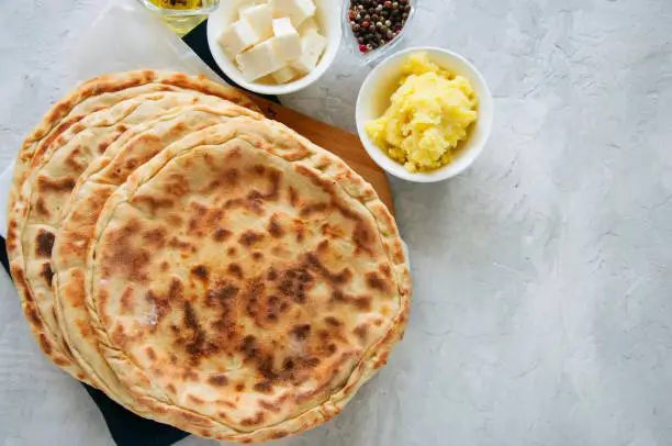 Mashed potato and sheep cheese filling flatbread on a white stone background.