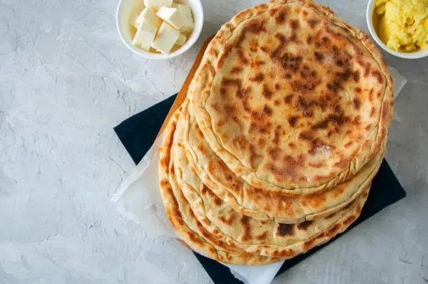 Mashed potato and sheep cheese filling flatbread on a white stone background.