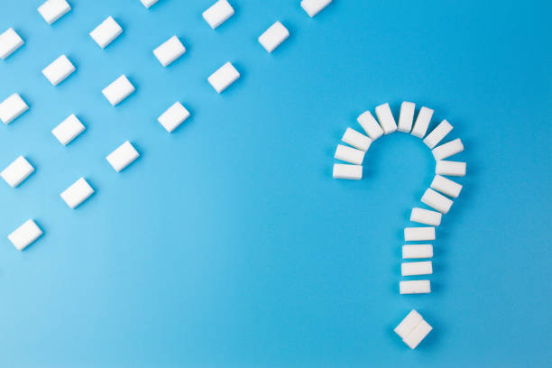 istock Sugar cubes shaped as a question mark sign on blue background. 910853044