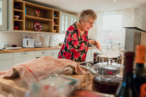 A senior woman cooks a meal in the kitchen.