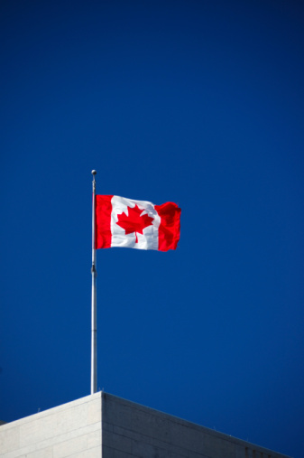 Canadian flag against blue sky.