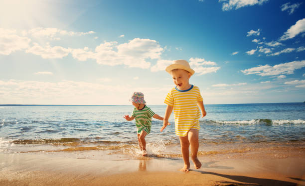 niño y niña jugando en la playa - child beach playing sun fotografías e imágenes de stock