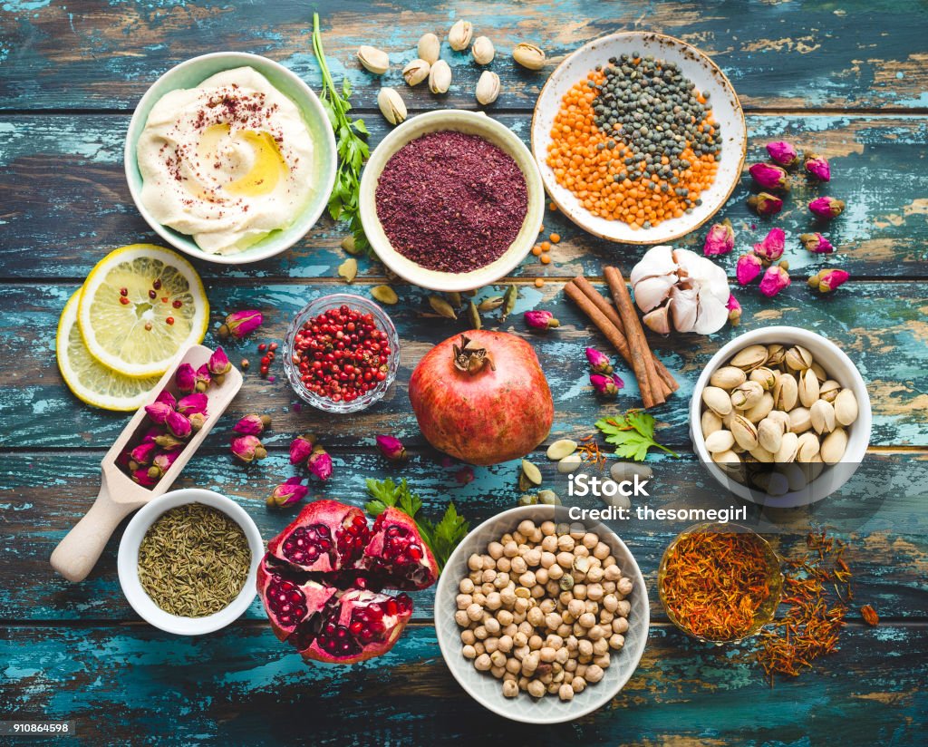 Arab ingredients for middle eastern food Arab ingredients for middle eastern food. Arabic cuisine ingredients on blue wooden background. Hummus, chickpea, lentils, rose buds, spices, pomegranate, pistachios. Halal food making. Top view Food Stock Photo