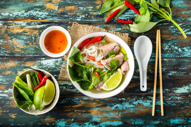 Vietnamese soup pho bo Traditional Vietnamese soup Pho bo with herbs, meat, rice noodles, broth. Pho bo in bowl with chopsticks, spoon. Space for text. Top view. Asian soup Pho bo on wooden table background. Vietnamese soup noodle soup photos stock pictures, royalty-free photos & images