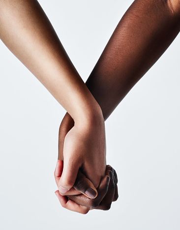 Cropped studio shot of two women holding hands