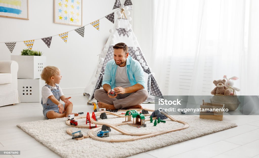 feliz padre y niño hijo de familia jugando en ferrocarril del juguete en la sala de juegos - Foto de stock de Niño libre de derechos