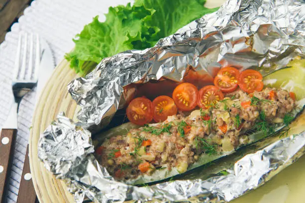 Half of zucchini stuffed with minced turkey, poultry and grated vegetables and foil baked in oven. With salad and tomatoes on the side.