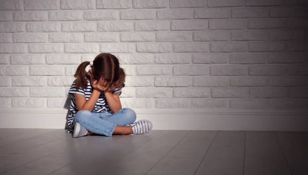 upset sad sad child girl in stress cries at an empty dark wall - domestic violence imagens e fotografias de stock