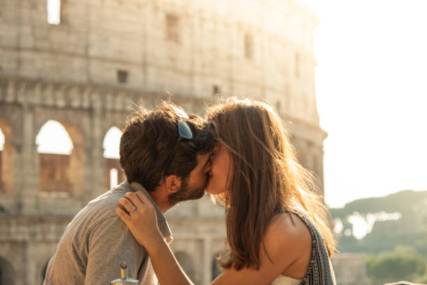 turismo joven romántica pareja feliz en el amor besos caricias frente a coliseo de roma al atardecer con destello de lente - lens box fotografías e imágenes de stock