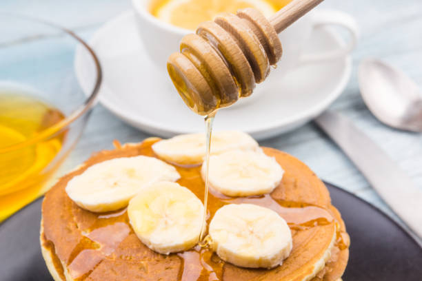 istock Pour honey on pancakes with bananas close-up 910879932